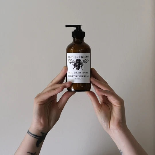 Two hands holding up a glass amber jar of lotion with a black pump.