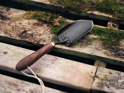 The trowel sitting on a mossy wooden pallet.