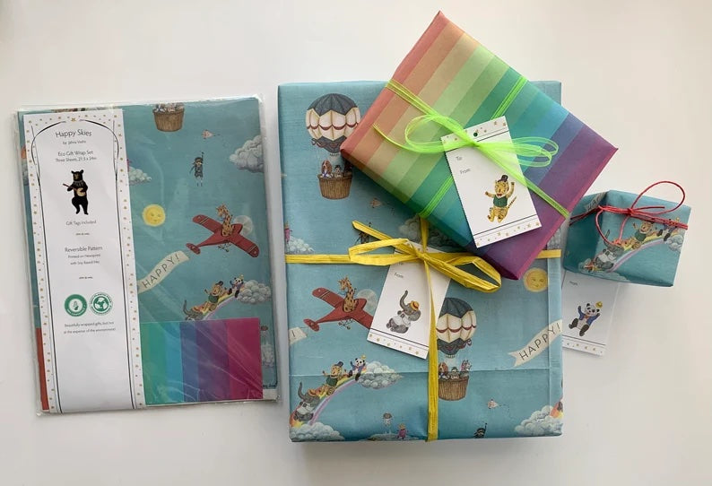 Blue gift wrap with animals in planes, hot air balloons, and rainbows. A few gift tags with animals are also visible along with rainbow gift wrap.
