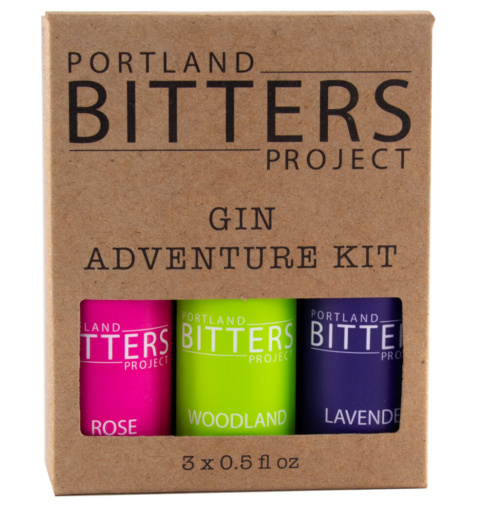 A brown box holding 3 of Portland Bitters Project's bitters. The label indicates that this is a Gin Adventure Kit. The labels of the bottles are pink, green, and purple.