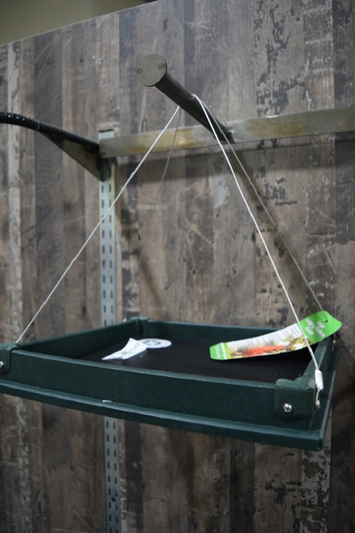 A green hanging feeder. It is flat and has black mesh in the center.