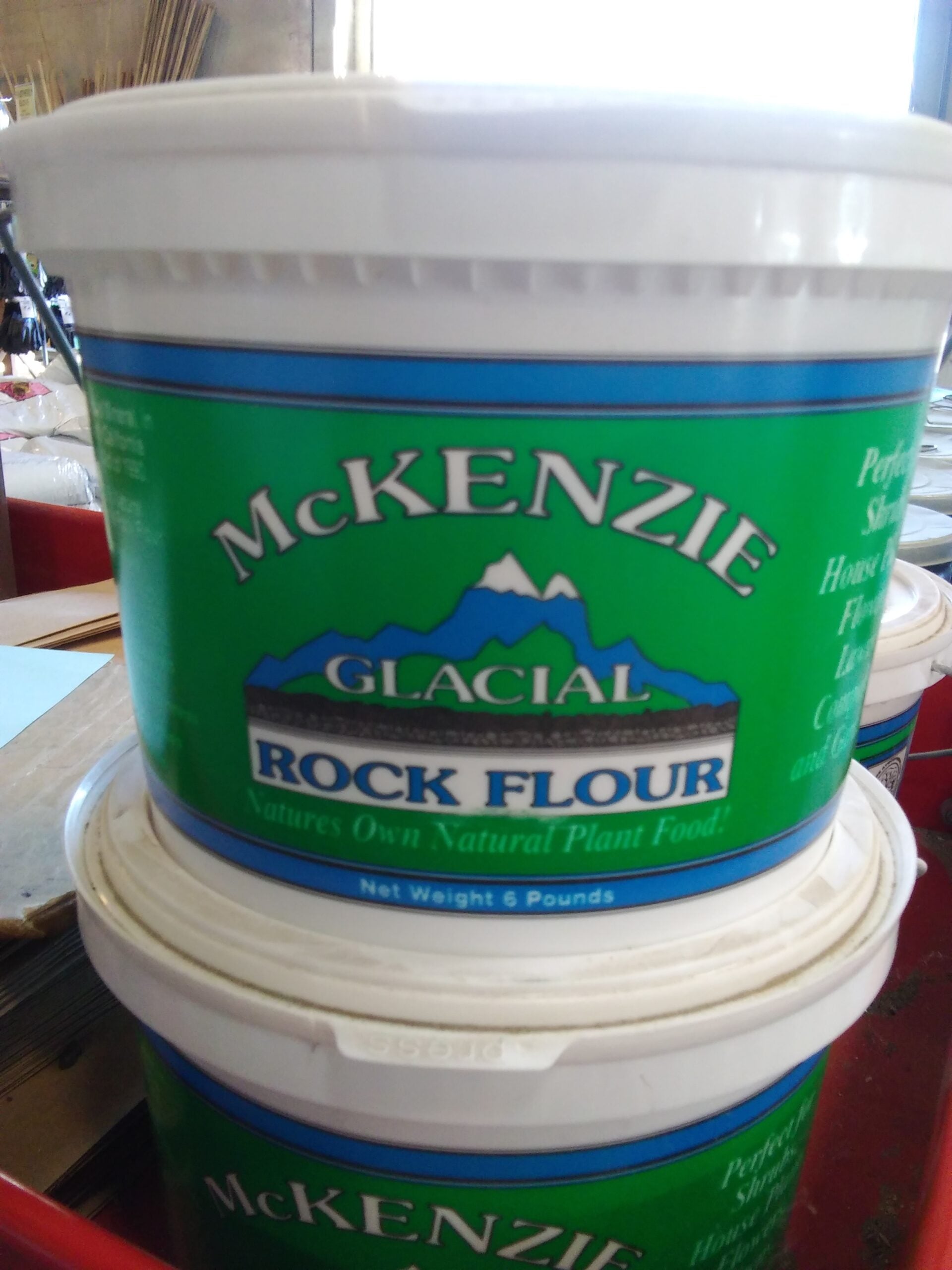 White containers with a green and blue label. There is an illustration of 2 mountain peaks.