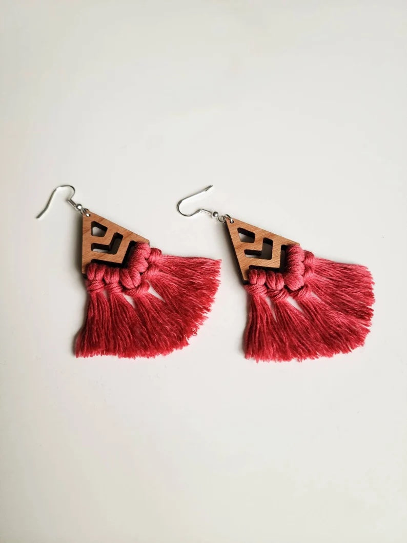 Earrings with a chevron-style wooden design that connects to a pink tassel.