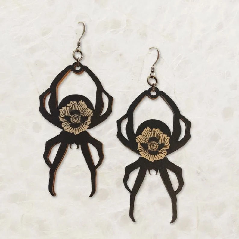 Black spider earrings with a white flower etched in the center.