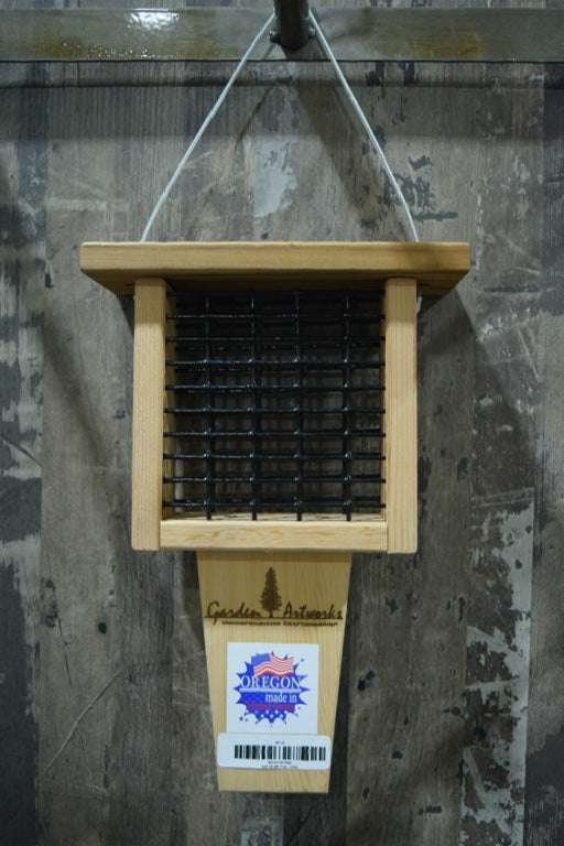 A light brown suet feeder with a tail prop. There is back mesh where the suet cake is held.